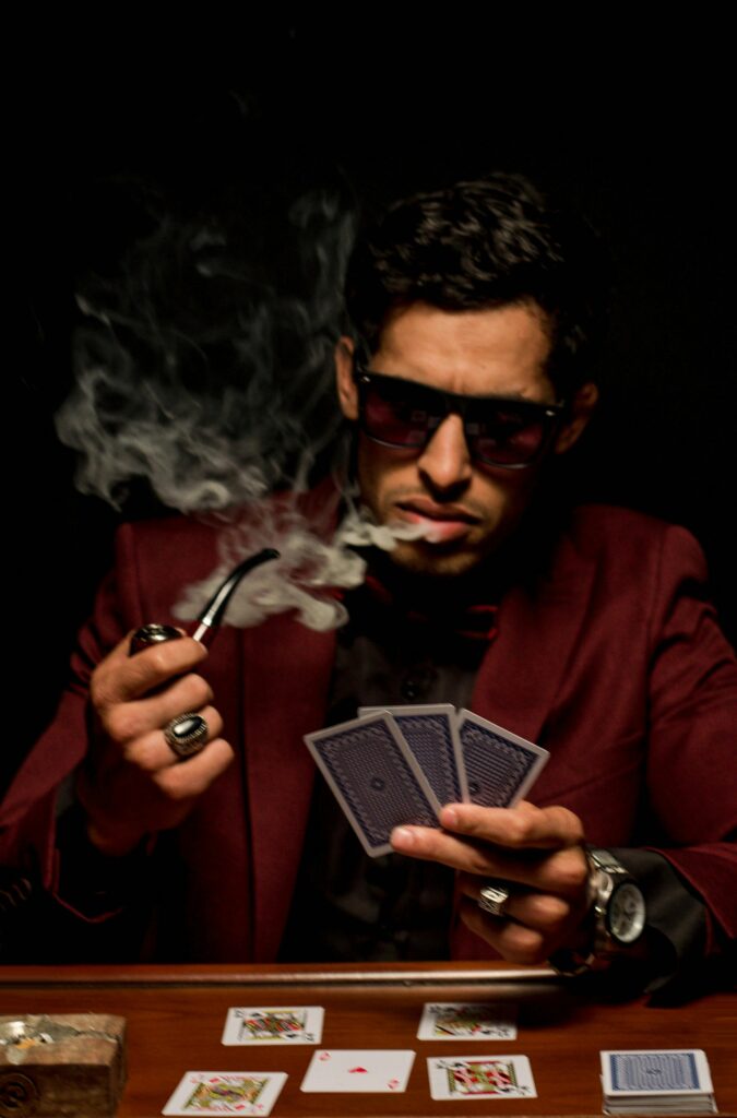 Poker player in sunglasses reading his cards and smoking his pipe